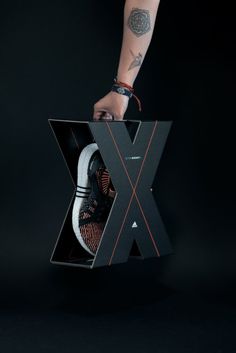 a person is holding a box with a pair of sneakers in it and the letter x inside