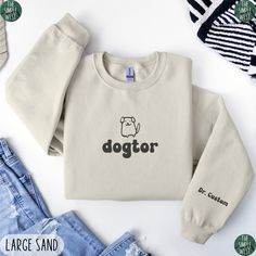 Looking for a comfortable and fun way to show off your love for both dogs and medicine? Look no further than this Custom Dogtor Sweatshirt! This funny vet sweatshirt is the perfect way to show off your profession and passion for dogs. It's a great gift for any future veterinarian or veterinary student, too! IMPORTANT INFORMATION - Custom text is printed on the outer part of the left sleeve - All Sales Are Final: refunds, returns, or exchanges are not available since each item is made to order. - Vet School Graduation, Future Veterinarian, Veterinary Student, Vet School, Gifts For Veterinarians, School Graduation, Funny Sweatshirts, Graduate School, Veterinarian