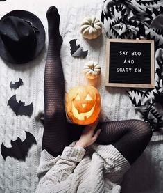 a woman laying on top of a bed next to a sign that says say boo and scary on