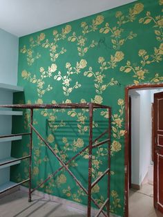 a room with green wallpaper and gold flowers on the wall next to a ladder