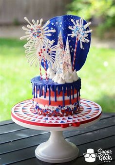 a red, white and blue cake with fireworks on it sitting on top of a table