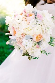 a bride holding a bouquet of white and pink flowers