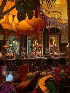 the interior of a fancy bar with lots of chairs and plants in front of it