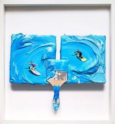 a painting is being displayed in a white frame with blue paint on it and two people riding surfboards