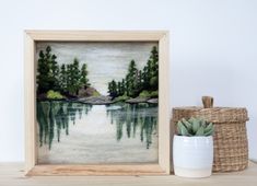 a painting in a wooden frame next to a potted succulent and basket