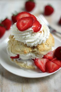 a white plate topped with strawberry shortcakes covered in whipped cream and strawberries