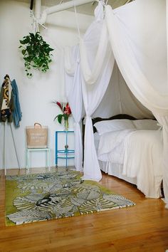 a bedroom with white curtains and a green rug on the floor next to a bed