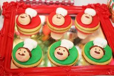 some cupcakes with frosting on them are in a red frame and decorated like monkeys