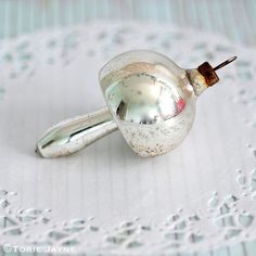 a small silver object sitting on top of a white table cloth covered in drops of water