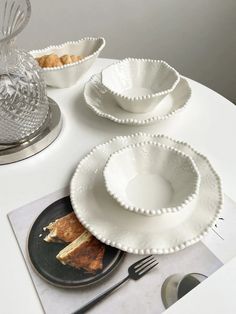 a white table topped with plates and bowls