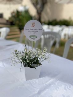 there is a small vase with flowers in it on top of a white table cloth