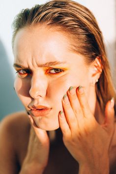 a woman with green and yellow nail polish holding her hand up to her face while looking at the camera