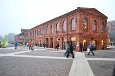 people are walking in front of an old brick building