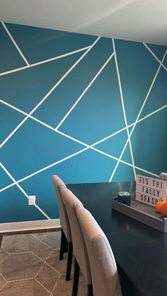 a dining room table with chairs and a wall painted in teal blue, white and grey