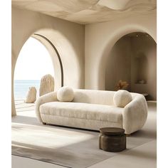 a large white couch sitting in front of an arched window on top of a floor