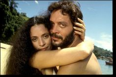 a man and woman hugging each other by the water