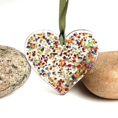 a heart shaped ornament sitting next to two rocks