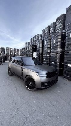 a range rover is parked in front of stacks of tires on the ground with sky background