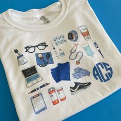 a white t - shirt with various items on it sitting on a blue table top