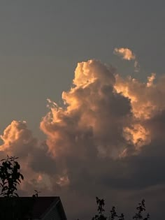 the sky is filled with clouds as the sun sets in the distance behind some trees