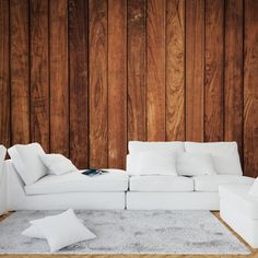 a white couch sitting on top of a rug next to a wooden wall and floor