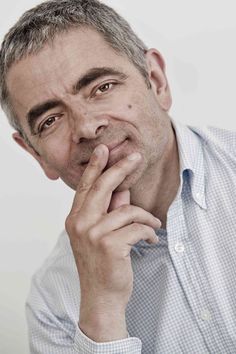 a close up of a person wearing a shirt and holding his hand to his chin