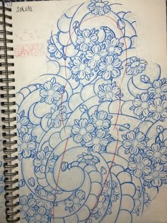 a spiral notebook with blue and red ink on it, containing an abstract design in the middle