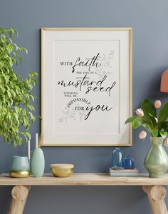 a wooden table topped with vases filled with flowers next to a framed quote on the wall