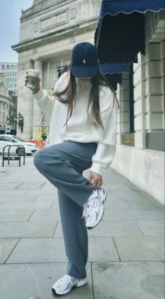 a woman sitting on the ground with an umbrella over her head and holding a coffee cup