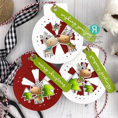 three christmas tags with reindeers on them next to some scissors and other holiday decorations