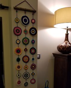 a wall hanging made out of crochet and yarn with a lamp next to it