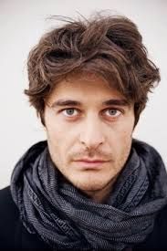 a close up of a person wearing a scarf and looking at the camera with an intense look on his face