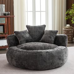 a living room with a large round chair in the middle and pillows on the bottom