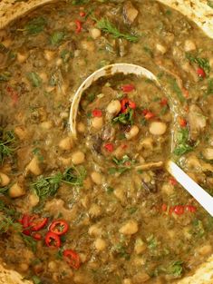 a bowl filled with beans and greens next to a spoon