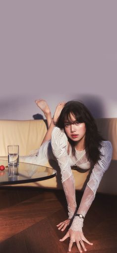 a woman laying on top of a wooden floor next to a glass table and couch