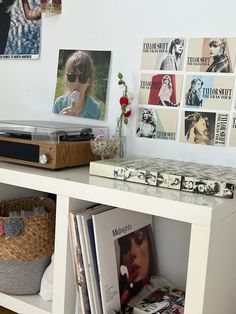 there is a shelf with books and magazines on it next to a wall with pictures