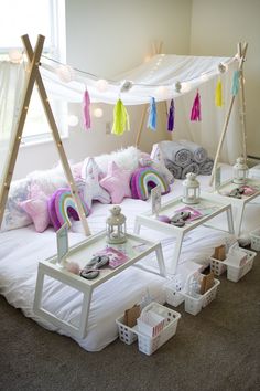 a white bed topped with lots of pillows next to a table filled with candy and candies