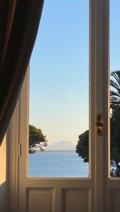 an open door leading to the ocean with trees and water in the backround