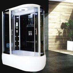 a white and black shower in a bathroom next to a potted plant on the floor