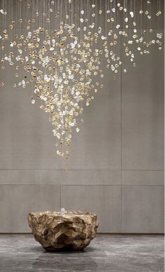 a large chandelier hanging from the ceiling over a stone bowl in front of a wall