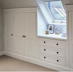 an attic bedroom with white cabinets and drawers