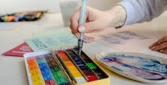 a person is painting with watercolors on a table