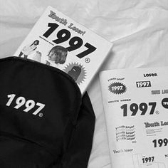 a book and backpack laying on top of a bed next to it's contents