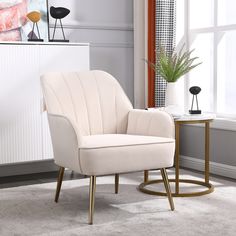 a white chair sitting in front of a window next to a table with a potted plant on it