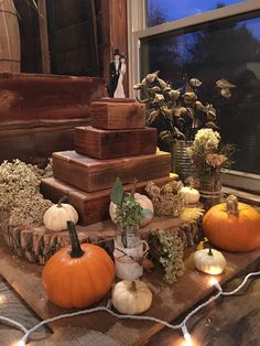 pumpkins and gourds are arranged on a table with string lights around them