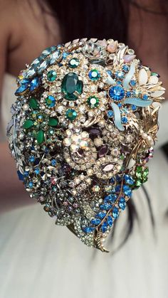 a close up of a person holding a bouquet with brooches and jewels on it