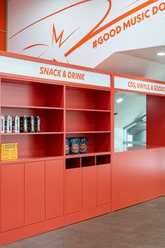 an orange book case with snacks and drinks on it's shelves in front of a sign that reads good music donuts