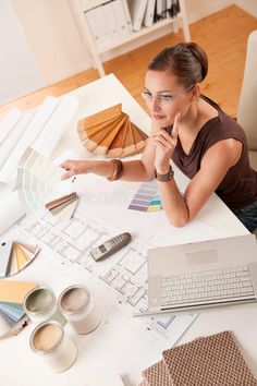 a woman sitting at a table with some paint samples and a laptop in front of her