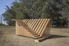 a wooden structure sitting in the middle of a field with stairs leading up to it