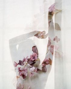 a white vase with pink flowers on it sitting in front of a window sill